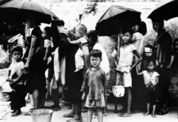 1962年5月拍摄的照片显示,逃离中国大饥荒的难民在香港排队领取食物。