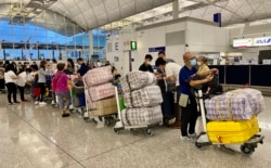 英国LOTR安排届满前夕,7月18日晚香港国际机场出现移居英国的人潮,他们推着堆积如山的行李,港人惯用的大型”红白蓝袋”成为机场特别的风景。 (美国之音/汤惠芸)