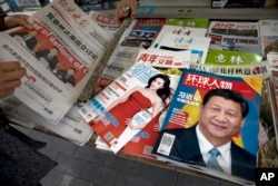 北京报摊上的报纸刊物,其中《环球人物》杂志的封面上有习近平照片和《习近平 中国强起来》的标题,还有报道中共十九大修改党章消息的北京晚报,也有以影视明星范冰冰为封面的《知音》杂志。(2017年10月21日)
