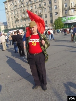 2012年5月普京再次就职总统前夕莫斯科爆发大规模反政府和反普京再次执政示威。一名示威者手举共产党红旗,身穿苏联标志服装表达他对苏联的怀恋。(美国之音白桦拍摄)