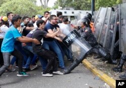 资料照片:委内瑞拉大学生在首都加拉加斯一次反马杜罗政府示威中试图夺走防暴警察的防护盾。(2019年11月14日)