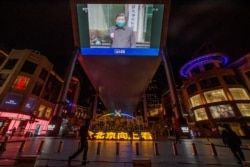 北京一家商场的电视屏幕上显示中央电视台播放的中国国家主席习近平视察武汉火神山医院的画面。(2020年3月10日)