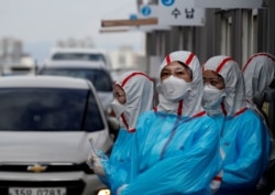 身穿防护服的韩国医护人员在一个检查站对开车通过的人进行新冠病毒感染检测。(2020年3月3日)