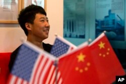 一位16岁的中国学生在北京一家教育机构里的美中两国国旗旁(2014年6月26日)