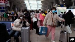 北京南站戴着口罩的旅客在候车室里等待。(2022年1月14日)