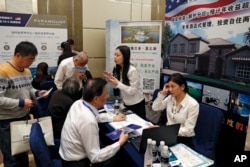 在妮可·库什纳(Nicole Kushner Meyer现身北京的一场投资移民项目(EB-5)推介会的一天之后,在投资美国展览中,在EB-5签证项目摊位上,中国人询问信息(2017年5月7日)
