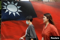 人们从台北街头的台湾旗帜旁走过。(2020年8月10日)