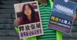 一名香港民主活动人士在中联办外手持上海维权人士、公民记者张展的照片。(2020年12月28日)