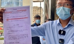 香港新同盟荃湾区议员谭凯邦展示一张香港市民接受中资公司中龙作免费病毒检测的”知情同意书”(美国之音/汤惠芸)