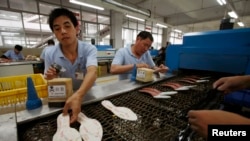 资料照片:2010年6月21日,在江西省赣州的一家鞋厂里,工人正在制作鞋底。