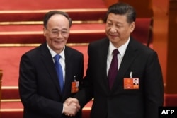 当选连任的中国国家主席习近平在中国第十三届全国人大全体会议上和当选中国国家副主席的王岐山握手(2018年3月17日)。