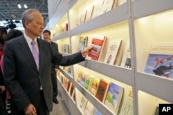 中国驻美大使崔天凯在纽约书展的中国摊位拿起一本论述中共在中国为何成功、如何成功的书(2015年5月27日)