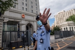 当押送任志强的警车抵达北京第二中级人民法院时一名警察在向记者做手式。(2020年9月11日)