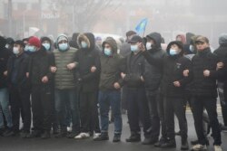 哈萨克斯坦的抗议民众在阿拉木图手挽手站在防暴警察前。(2022年1月5日)