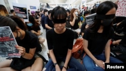 香港反送中示威者2019年8月12日在香港国际机场静坐示威时用黑布蒙眼,抗议警方一天前与示威者的冲突中使一名抗议者眼睛受伤。