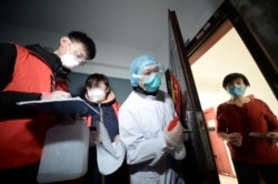 中国天津的社区工作人员和医疗人员挨门挨户地检查居民健康状况。(2020年2月12日)