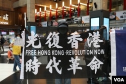 资料照:在台北车站参与支持香港行动的民众高举“光复香港时代革命”旗帜。 (2020年5月23日)