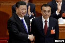 中国总理李克强在北京人大会堂召开的全国人大会议上获连任后与中国国家主席习近平握手。(2018年3月18日)