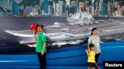 参观者在香港中国海军基地一副反映辽宁号航母的背景画面前拍照留影。(2017年7月8日)