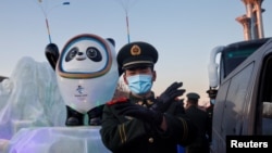 一名中国武警士兵在北京的冬奥会吉祥物前给拍照者做手势。(2022年1月15日)