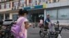 一个女孩站在北京街头一个新东方校外补习学校的附近。(2021年7月26日)