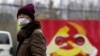 一名戴着口罩的男子走过上海街头一处中共徽标的图案。(2020年1月28日)