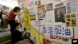 在台湾的香港学生为执行当地政府的指令从一面连侬墙上移走标语。(2019年8月31日)