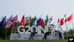 2023 年 7 月 13 日,在印度古吉拉特邦首府甘地讷格尔,工人们赶在G20峰会的一个工作组会议前安装峰会的标志。