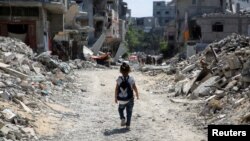 A Palestinian student walks between the rubble after attending a class in a tent set up on the rubble of the house of teacher Israa Abu Mustafa, as war disrupts school year, in Khan Younis, in the southern Gaza Strip, Sept. 4, 2024.