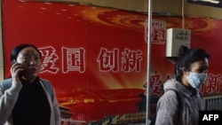 人们走过北京地铁站入口处的“爱国,创新”宣传广告牌(2018年10月19日)。