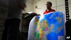 湖南长沙印刷工厂工人手持中国新正式批准的地图,其中包括北京声称在南中国海有用有权的岛屿
