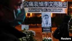 资料照:人们戴着口罩出席在香港设立的一处悼念在武汉中心医院病逝的李文亮医生。(2020年2月7日)