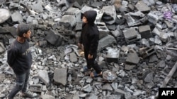 2025年1月1日,巴勒斯坦儿童在加沙地带杰巴利耶前一天晚上遭到以色列袭击的现场观察损坏的情况。