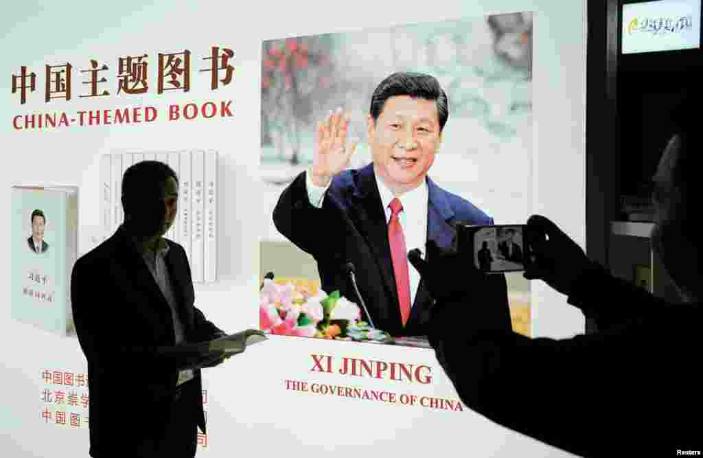2018年11月7日,在上海国家会展中心的中国国际进口博览会上中国国家主席习近平书籍展位,一名男子摆姿势拍照。
