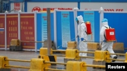 资料照片:世卫组织专家组在中国调查新冠病毒溯源期间工人在武汉白沙洲商场喷洒消毒液。(2021年1月31日)