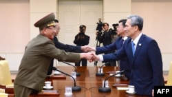 韩国总统的国家安全顾问金宽镇(右)与朝鲜军队的最高政治官(左)握手。