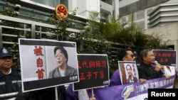 资料照:香港抗议者在北京驻香港机构中联办前手举铜锣湾书店失踪老板桂民海的照片。 (2016年1月19日)