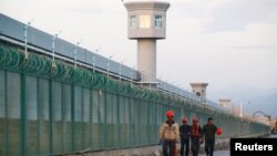 中国新疆维吾尔自治区达坂城的官方所谓的职业技能教育中心的围栏旁边,有工人走过。(2018年9月4日)