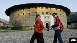 资料照:学童们走过福建省永定县洪坑村的客家土楼“振成楼”。(2005年12月15日)