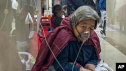 资料照片:2023年1月5日,一名老年患者在北京急诊病房走廊带着呼吸机接受静脉滴注。(美联社照片)
