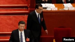 中国总理李克强在北京人大会堂举行的全国人大年度会议开幕式上发表讲话后返回习近平旁的座位。(2020年5月22日)