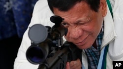 在中国把数以千计的狙击步枪和子弹移交菲律宾的仪式上,菲律宾总统杜特尔特观察中国步枪(2017年6月28日)。