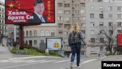 塞尔维亚一名女子走过贝尔格莱德街头树立的感谢中国领导人习近平的广告牌旁。(2020年4月1日)