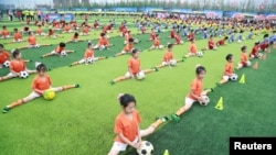 2016年7月16日,在辽宁省大连市的一个足球活动开幕仪式上,学生们进行足球表演。