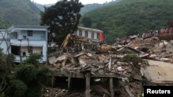 铲土机在云南昭通鲁甸县的地震灾区现场清除废墟,寻找遇难者遗体。(2014年8月5日)