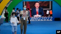 一名女子带着孩子走过北京一处宣传习近平的电子屏幕广告。(2021年9月5日)