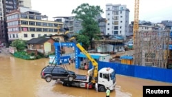 中国广西柳州市的交通警察把街道上泡在洪水里的汽车运走。(2021年7月2日)