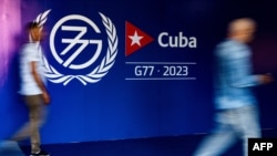 2023年9月13日,哈瓦那新闻发布厅开幕期间,人们走在77国集团+中国峰会的标志附近. (法新社)