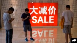 资料照片;中国购物者站在购物区的促销广告附近。