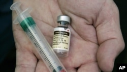 FILE - A doctor holds a vial of the human papillomavirus (HPV) vaccine Gardasil in his Chicago office.